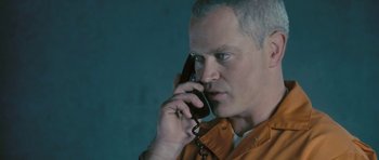 Movie still from “88 Minutes” (2007), directed by Jon Avnet – A man in an orange shirt talking on a phone; Close Up shot, Low angle