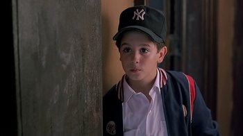 Movie still from “A Bronx Tale” (1993), directed by Robert De Niro – A young boy wearing a baseball cap and jacket; Close Up shot, Over the shoulder angle