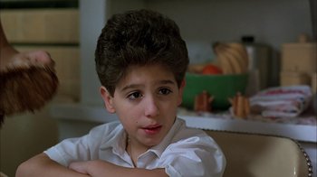 Movie still from “A Bronx Tale” (1993), directed by Robert De Niro – A young boy sitting in front of a table; Close Up shot, Low angle