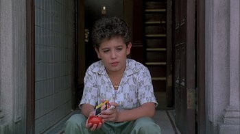 Movie still from “A Bronx Tale” (1993), directed by Robert De Niro – A young boy sitting on the ground holding a tomato; Close Up shot, High angle