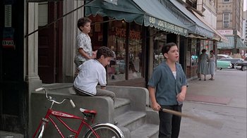 Movie still from “A Bronx Tale” (1993), directed by Robert De Niro – Three young boys are playing baseball on the steps; Wide shot, High angle