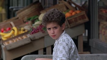Movie still from “A Bronx Tale” (1993), directed by Robert De Niro – A young man sitting in front of a fruit stand; Close Up shot, Low angle