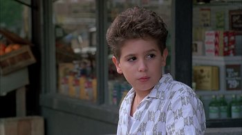 Movie still from “A Bronx Tale” (1993), directed by Robert De Niro – A young boy in a white shirt is looking at the camera; Close Up shot, Low angle