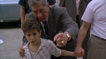Movie still from “A Bronx Tale” (1993), directed by Robert De Niro – An older man and a young boy holding hands; Medium shot, Low angle
