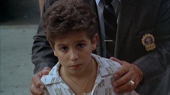 Movie still from “A Bronx Tale” (1993), directed by Robert De Niro – A young boy is being hugged by a man; Close Up shot, High angle