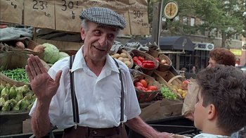 Movie still from “A Bronx Tale” (1993), directed by Robert De Niro – An older man wearing a hat standing in front of vegetables; Medium shot, Low angle