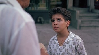 Movie still from “A Bronx Tale” (1993), directed by Robert De Niro – A young boy in a white shirt is looking at a man; Close Up shot, Over the shoulder angle