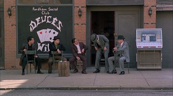 Movie still from “A Bronx Tale” (1993), directed by Robert De Niro – A group of men sitting on top of a wooden bench; Wide shot, High angle