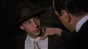 Movie still from “A Bronx Tale” (1993), directed by Robert De Niro – A man in a suit and a hat and a man in a tie; Close Up shot, Over the shoulder angle