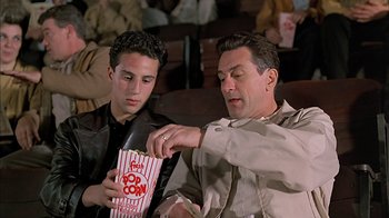 Movie still from “A Bronx Tale” (1993), directed by Robert De Niro – A man and a boy are eating popcorn; Medium shot, Low angle