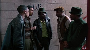 Movie still from “A Bronx Tale” (1993), directed by Robert De Niro – A group of young men standing next to each other in front of a brick wall; Medium shot, Low angle