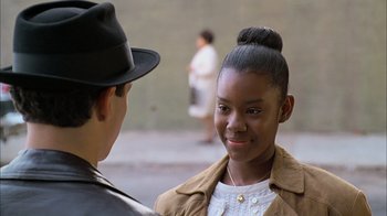 Movie still from “A Bronx Tale” (1993), directed by Robert De Niro – A young woman wearing a hat and a jacket; Close Up shot, Over the shoulder angle