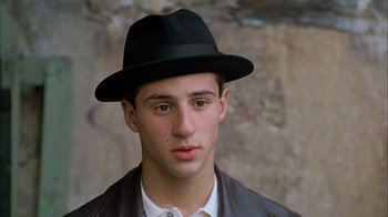 Movie still from “A Bronx Tale” (1993), directed by Robert De Niro – A young man wearing a black hat and a white shirt; Close Up shot, High angle