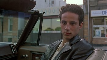 Movie still from “A Bronx Tale” (1993), directed by Robert De Niro – A man sitting in the driver's seat of a car; Close Up shot, Low angle