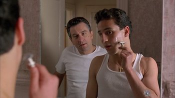 Movie still from “A Bronx Tale” (1993), directed by Robert De Niro – A man looking in a mirror while another man looks on; Close Up shot, Low angle