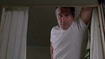 Movie still from “A Bronx Tale” (1993), directed by Robert De Niro – A man in a white t - shirt is standing under a curtain; Medium shot, Low angle