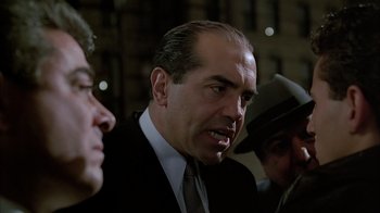 Movie still from “A Bronx Tale” (1993), directed by Robert De Niro – A man in a suit and tie talking to another man in a suit and tie; Medium shot, Over the shoulder angle