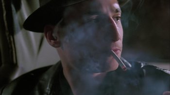 Movie still from “A Bronx Tale” (1993), directed by Robert De Niro – A man in a hat is smoking a cigarette; Close Up shot, Low angle