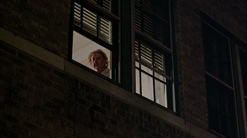 Movie still from “A Bronx Tale” (1993), directed by Robert De Niro – An older woman looking out of a window at night; Medium shot, Low angle