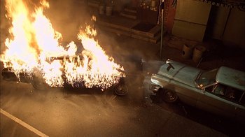 Movie still from “A Bronx Tale” (1993), directed by Robert De Niro – A car that is on fire on the side of the road; Wide shot, Overhead angle
