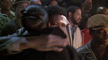 Movie still from “A Bronx Tale” (1993), directed by Robert De Niro – A group of people hugging each other in front of a crowd; Close Up shot, Over the shoulder angle