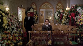 Movie still from “A Bronx Tale” (1993), directed by Robert De Niro – Two men in suits sitting in front of pews in a church; Wide shot, Low angle