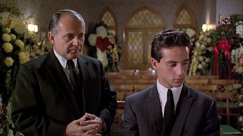 Movie still from “A Bronx Tale” (1993), directed by Robert De Niro – Two men in suits and ties in front of a church altar; Medium shot, Low angle