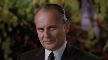 Movie still from “A Bronx Tale” (1993), directed by Robert De Niro – An older man wearing a suit and tie in front of flowers; Close Up shot, Low angle