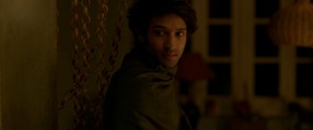 Movie still from “A Death in the Gunj” (2016), directed by Konkona Sen Sharma – A young man with long dark hair wearing a green jacket; Medium shot, Over the shoulder angle