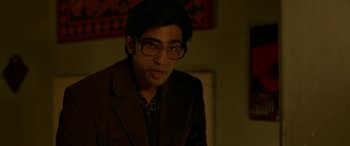 Movie still from “A Death in the Gunj” (2016), directed by Konkona Sen Sharma – A man in a brown jacket wearing glasses and a plaid shirt; Close Up shot, Low angle