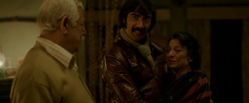 Movie still from “A Death in the Gunj” (2016), directed by Konkona Sen Sharma – A man in a brown leather jacket standing next to two other men; Medium shot, High angle