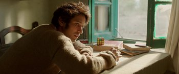 Movie still from “A Death in the Gunj” (2016), directed by Konkona Sen Sharma – A man sitting at a table with a rubiks cube in front of a window; Close Up shot, High angle