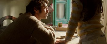 Movie still from “A Death in the Gunj” (2016), directed by Konkona Sen Sharma – A man sitting in front of a woman with a rubiks cube in his hand; Medium shot, High angle