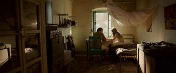 Movie still from “A Death in the Gunj” (2016), directed by Konkona Sen Sharma – A man and a woman sitting at a table in front of a window; Wide shot, High angle