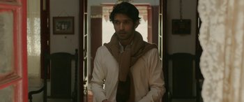 Movie still from “A Death in the Gunj” (2016), directed by Konkona Sen Sharma – A man in a white shirt wearing a brown scarf; Medium shot, Low angle