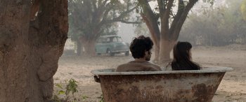 Movie still from “A Death in the Gunj” (2016), directed by Konkona Sen Sharma – A man sitting in an old bathtub in the middle of a dirt field; Wide shot, High angle