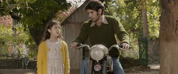 Movie still from “A Death in the Gunj” (2016), directed by Konkona Sen Sharma – A man riding a motorcycle with a little girl; Medium shot, Over the shoulder angle