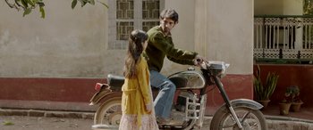 Movie still from “A Death in the Gunj” (2016), directed by Konkona Sen Sharma – A man and a little girl are on a motorcycle; Medium shot, High angle