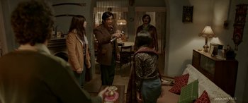 Movie still from “A Death in the Gunj” (2016), directed by Konkona Sen Sharma – A group of people standing in a living room; Medium shot, Over the shoulder angle