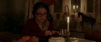 Movie still from “A Death in the Gunj” (2016), directed by Konkona Sen Sharma – An older woman sitting at a table with a lit candle; Close Up shot, High angle