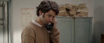 Movie still from “A Death in the Gunj” (2016), directed by Konkona Sen Sharma – A man talking on a phone while wearing a sweater; Close Up shot, Over the shoulder angle
