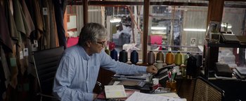 Movie still from “A Fantastic Woman” (2017), directed by Sebastián Lelio – An older man sitting at a table with papers and a phone; Medium shot, Over the shoulder angle