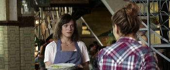 Movie still from “A Fantastic Woman” (2017), directed by Sebastián Lelio – A woman wearing an apron is holding a plate; Close Up shot, Over the shoulder angle