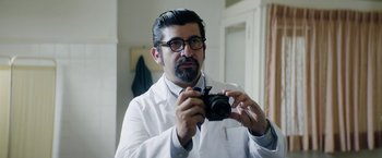 Movie still from “A Fantastic Woman” (2017), directed by Sebastián Lelio – A man in a white lab coat taking a picture; Close Up shot, Low angle