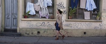 Movie still from “A Fantastic Woman” (2017), directed by Sebastián Lelio – A woman walking down the sidewalk in front of a building; Wide shot, Low angle