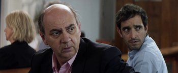 Movie still from “A Fantastic Woman” (2017), directed by Sebastián Lelio – A man in a pink shirt and black jacket and another man in a black suit; Close Up shot, Over the shoulder angle