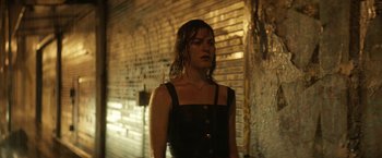 Movie still from “A Fantastic Woman” (2017), directed by Sebastián Lelio – A woman standing in the rain in front of a brick wall; Medium shot, Low angle