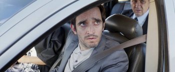 Movie still from “A Fantastic Woman” (2017), directed by Sebastián Lelio – A person sitting in a car wearing a suit; Close Up shot, Over the shoulder angle