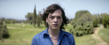 Movie still from “A Fantastic Woman” (2017), directed by Sebastián Lelio – A woman in a blue shirt is standing in the grass; Close Up shot, Over the shoulder angle