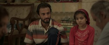 Movie still from “A Hero” (2021), directed by Asghar Farhadi – A man sitting next to a woman in front of a bookshelf; Close Up shot, High angle